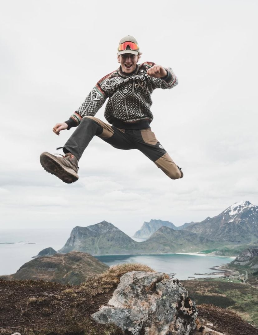 &Aring;dne Birkeland jumping on a mountain in Lofoten wearing a knitted 1994 Olympic sweater